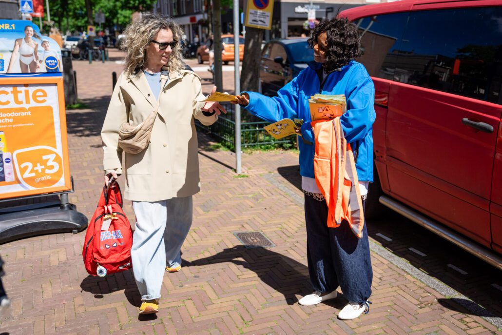 Een afvalcoach deelt een folder uit.
